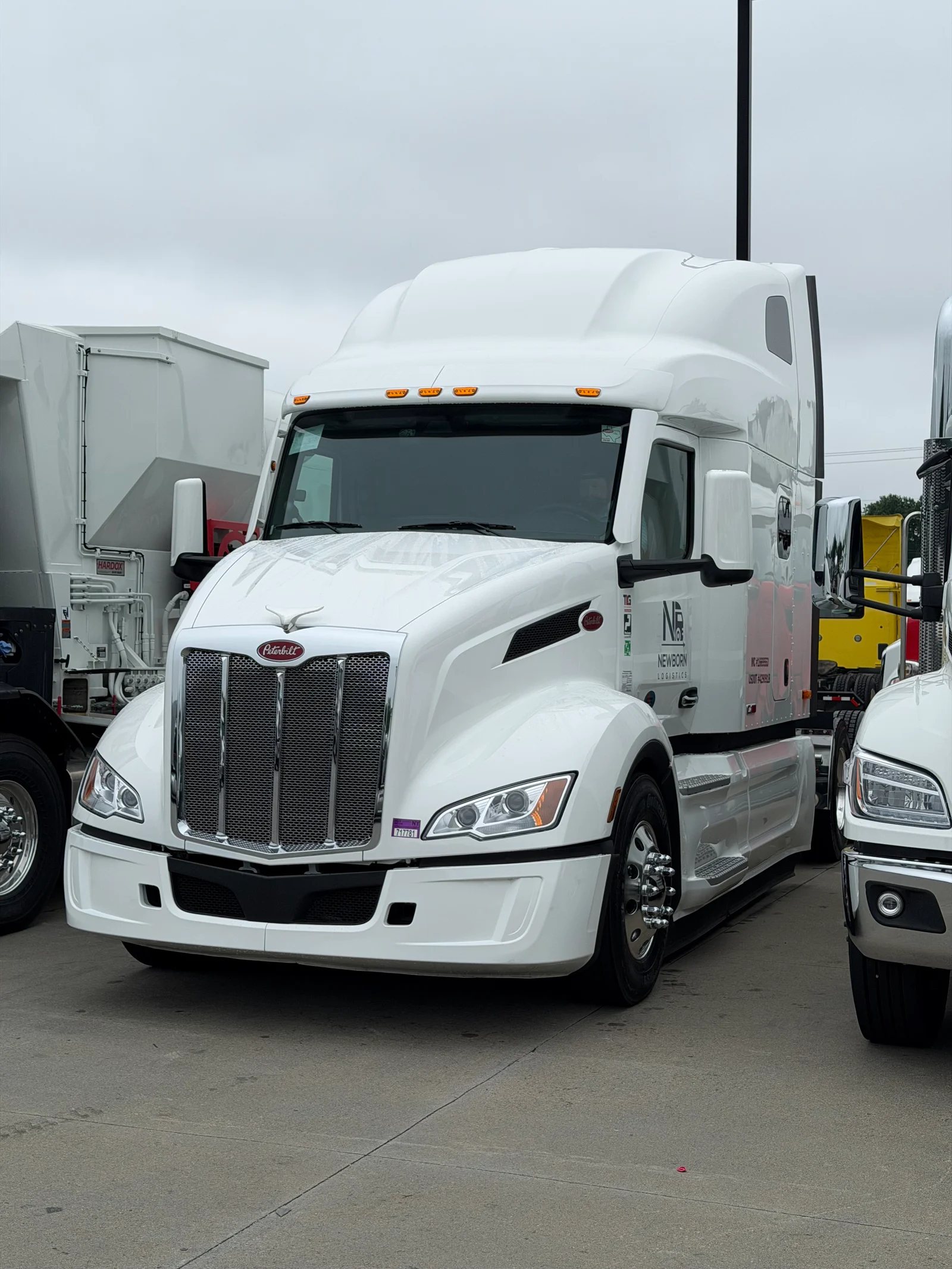 White Newborn Logistics Peterbilt tractor viewed from the front and driver side